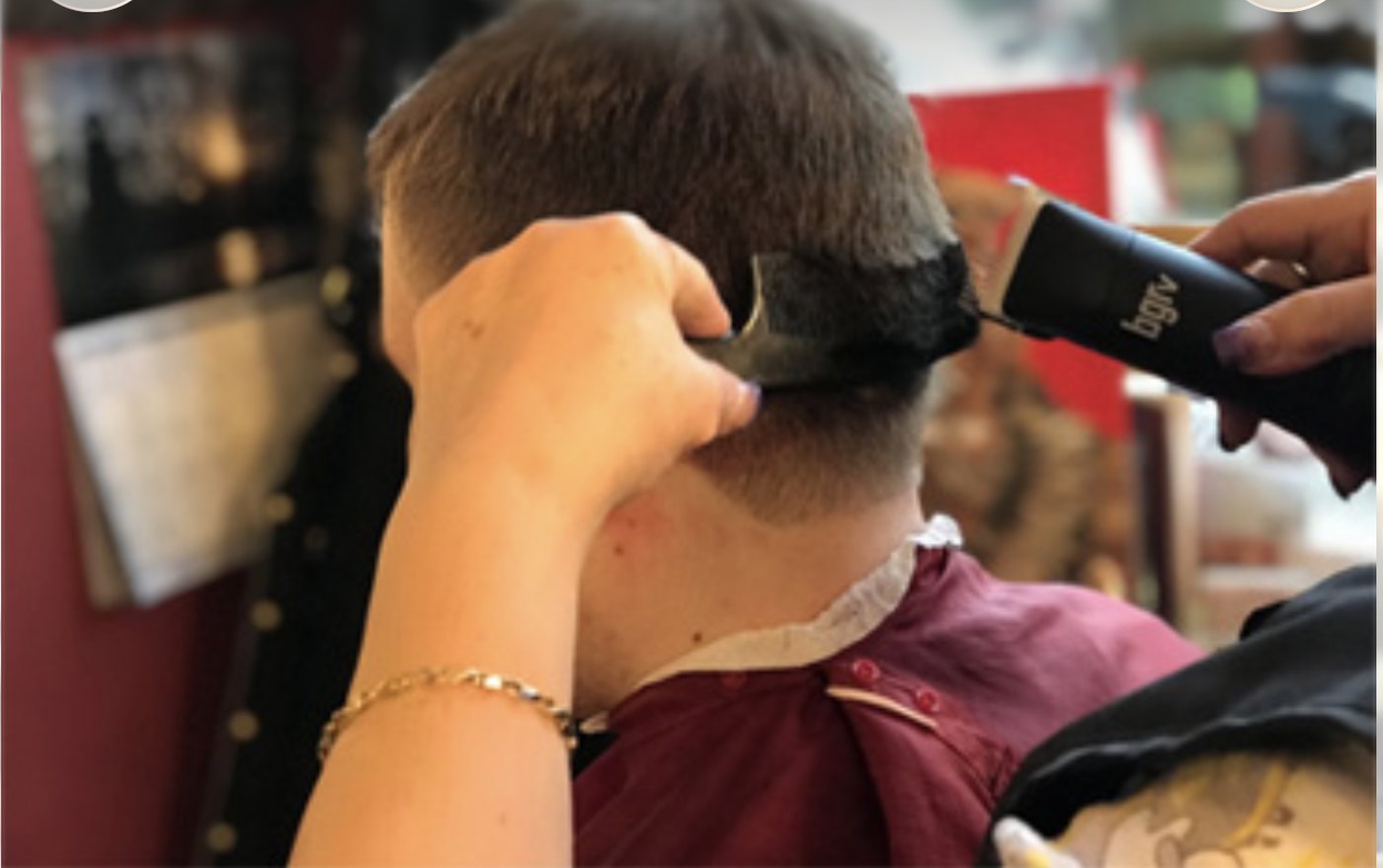 A barber tapering hair over a comb with clippers