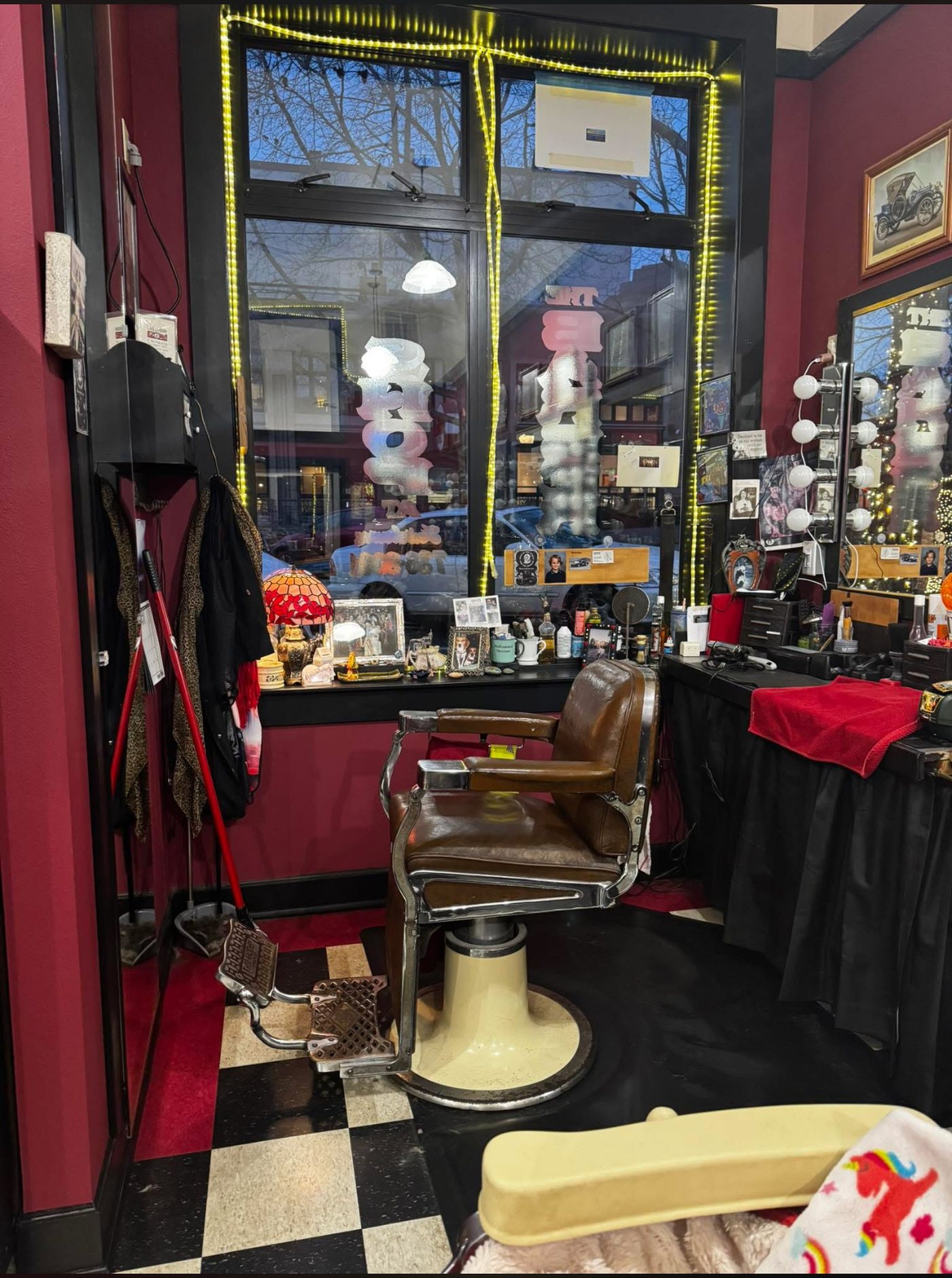 The shop interior: oxblood walls, checkerboard floor and a vintage leather barber chair by the window