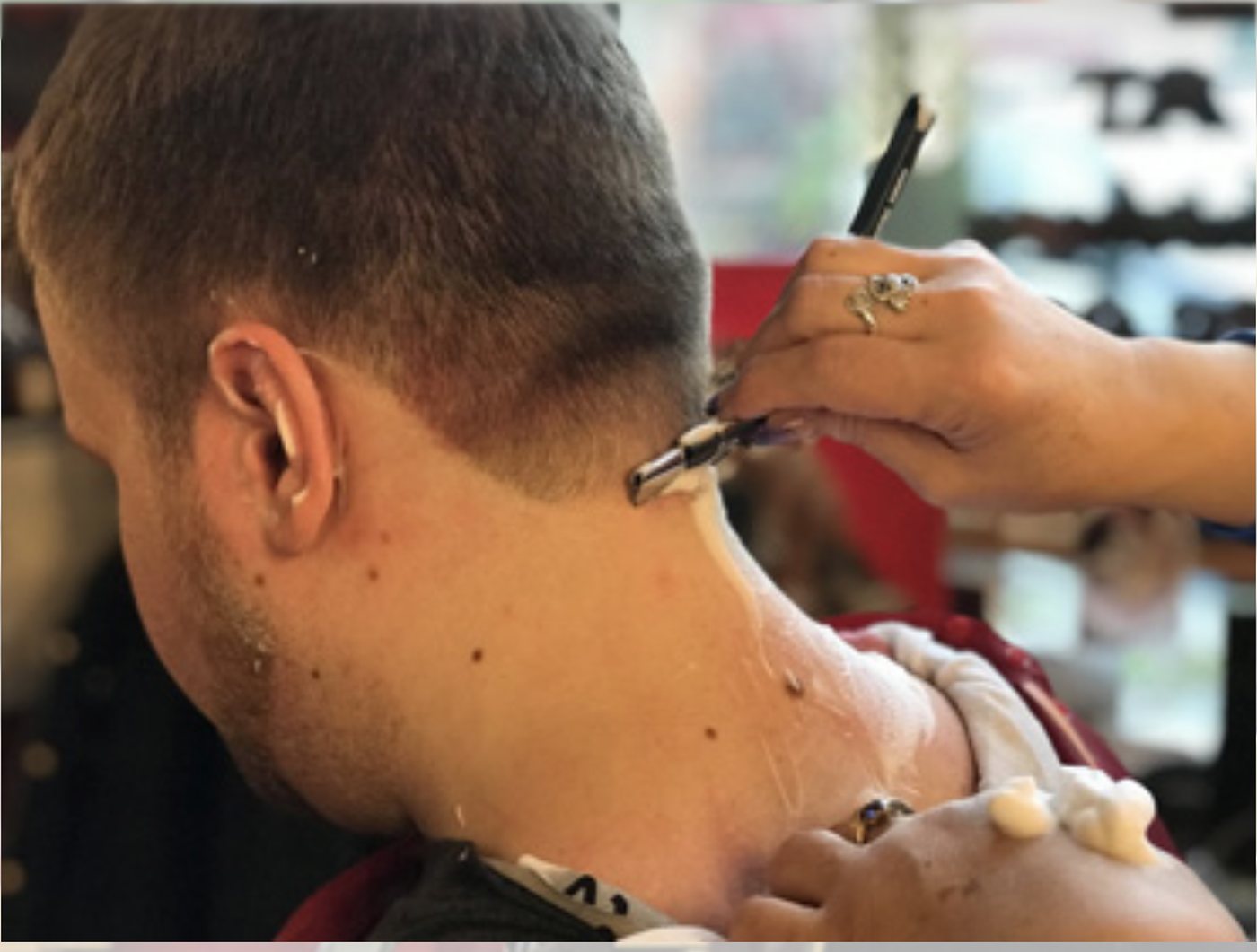 A barber finishing a neck shave with a straight razor and hot lather